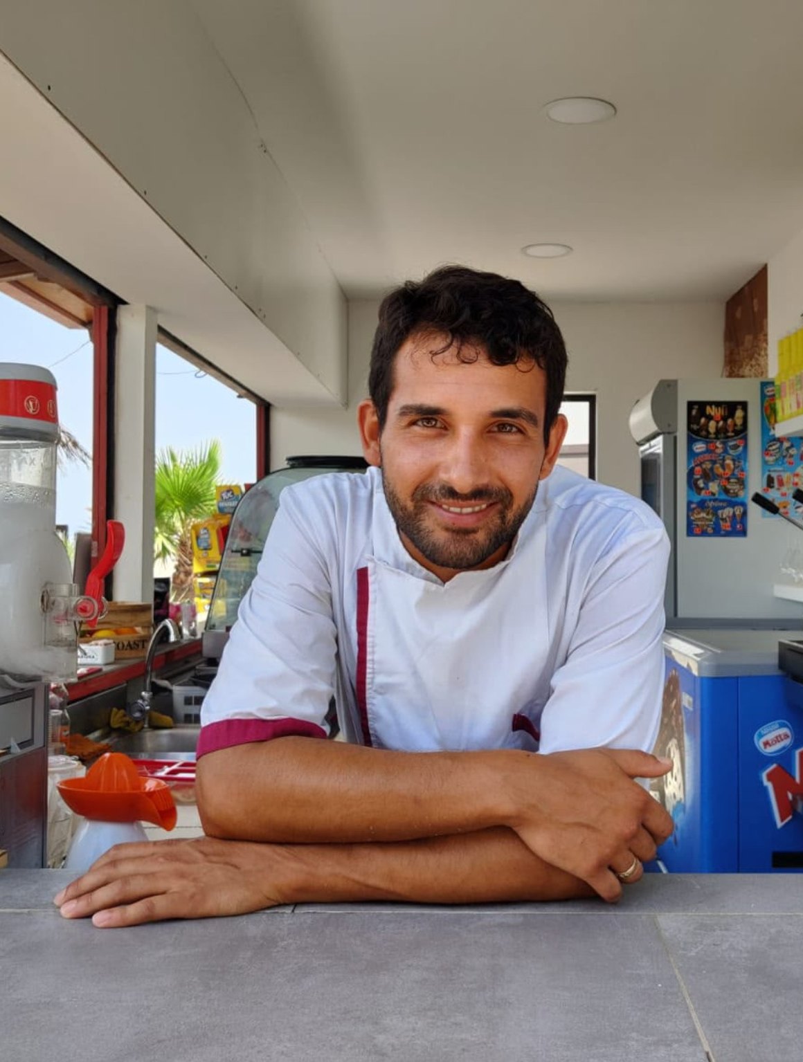 Alessandro Conte in giacca da chef, appoggiato al bancone del suo locale a Paola
